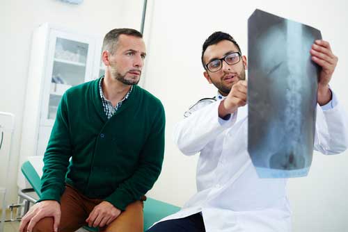 A doctor reviewing a spinal cord injury x ray with a patient.