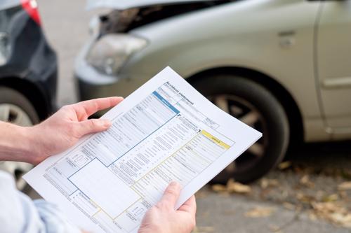 An insurance adjuster reviewing damage to a car after an accident.