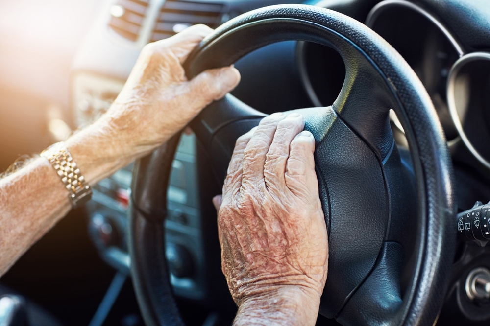 Close-up of an elderly driver's hands gripping a steering wheel, representing accident risks in an Atlanta wrongful death claim.