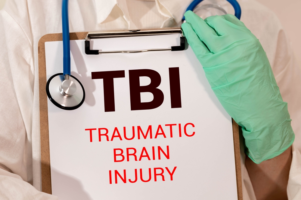 Doctor holding clipboard labeled traumatic brain injury TBI during medical evaluation