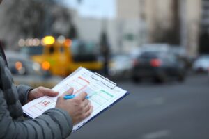 A man a jotting down the information in a report after accident