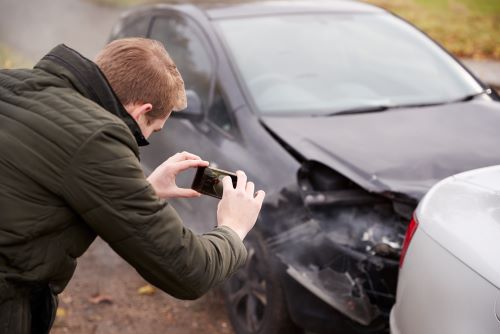 Man taking photos, gathering evidence after car crash