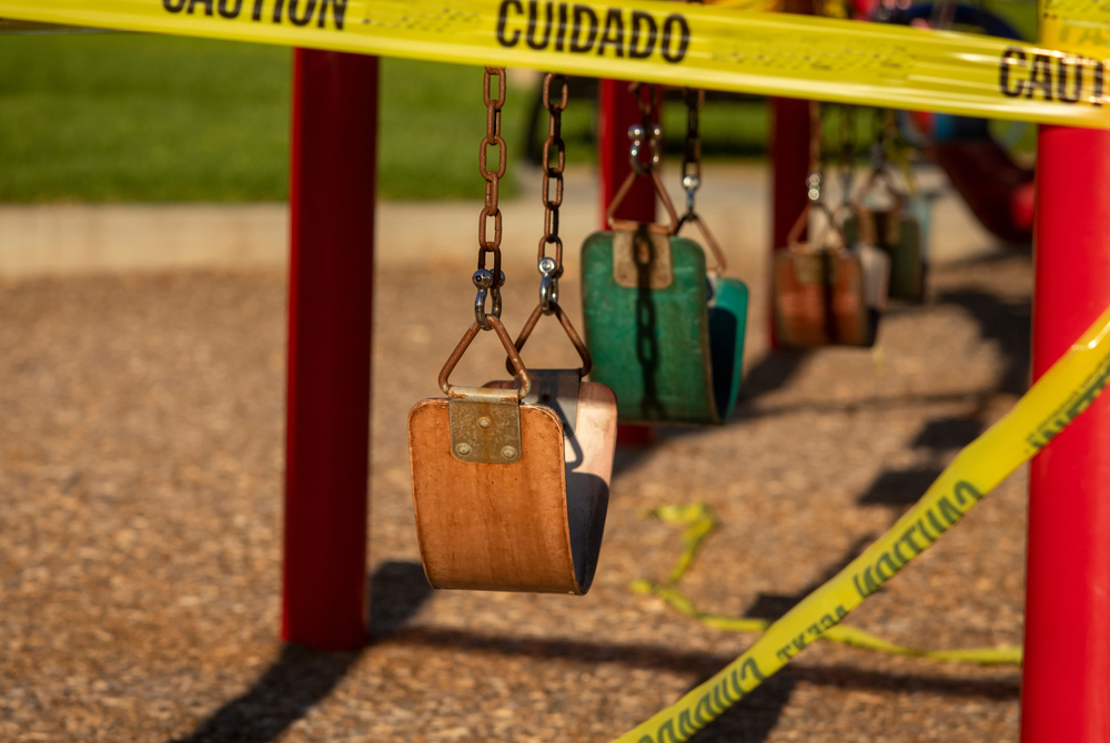 Playground swings blocked off with caution tape, representing hazardous conditions that can cause injuries on Albany properties.