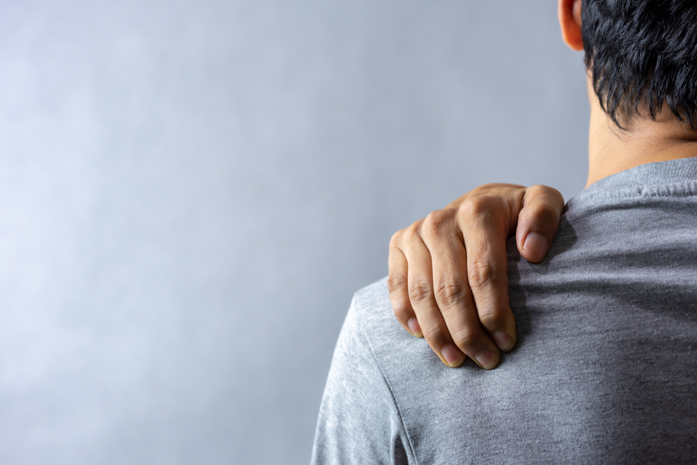 How To Claim Pain and Suffering From an Auto Crash 2 Person holding their shoulder in visible discomfort following an injury
