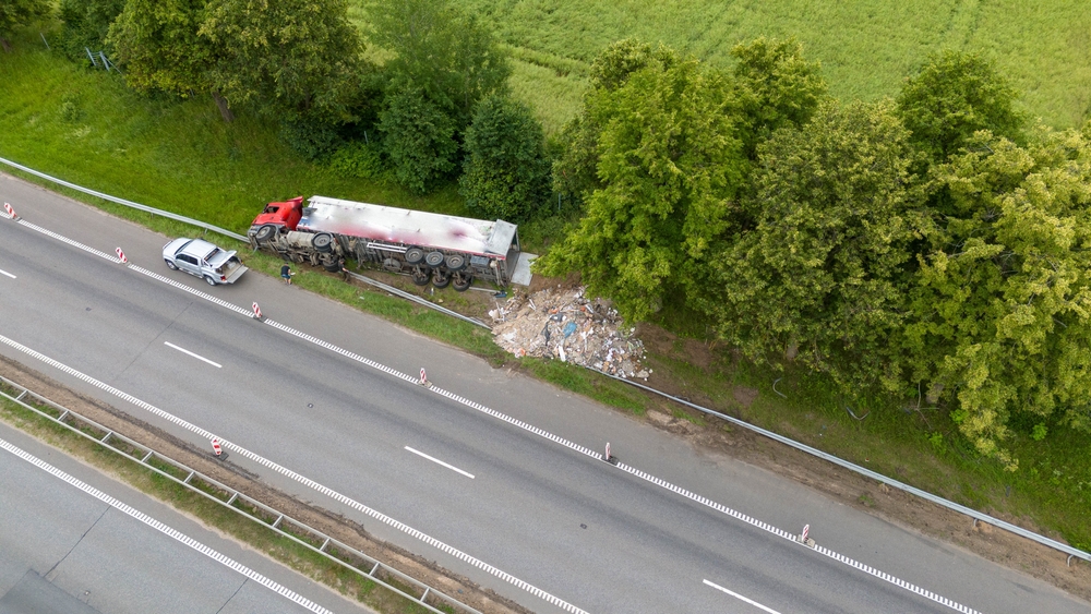 Jackknife semi-truck crash with trailer off the road beside a highway.